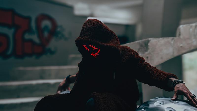 A Person Wearing A Hood And Mask In Alley 5k